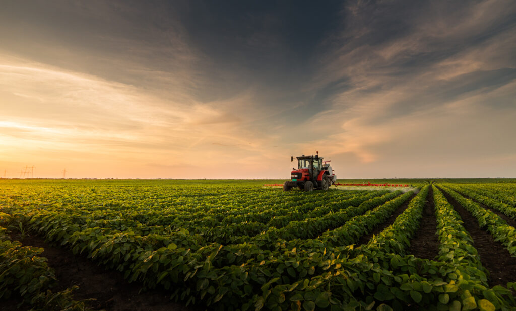 Tractor spraying pesticides on soybean field with sprayer at spring